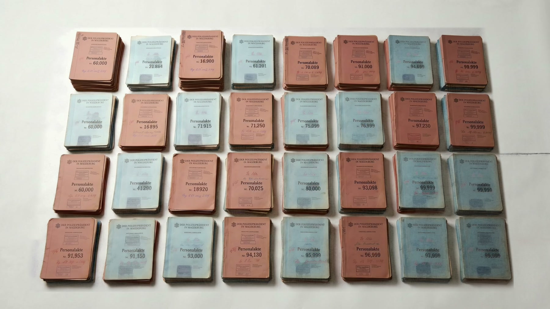 Film still: rows of pink and blue registration files laid out in a grid