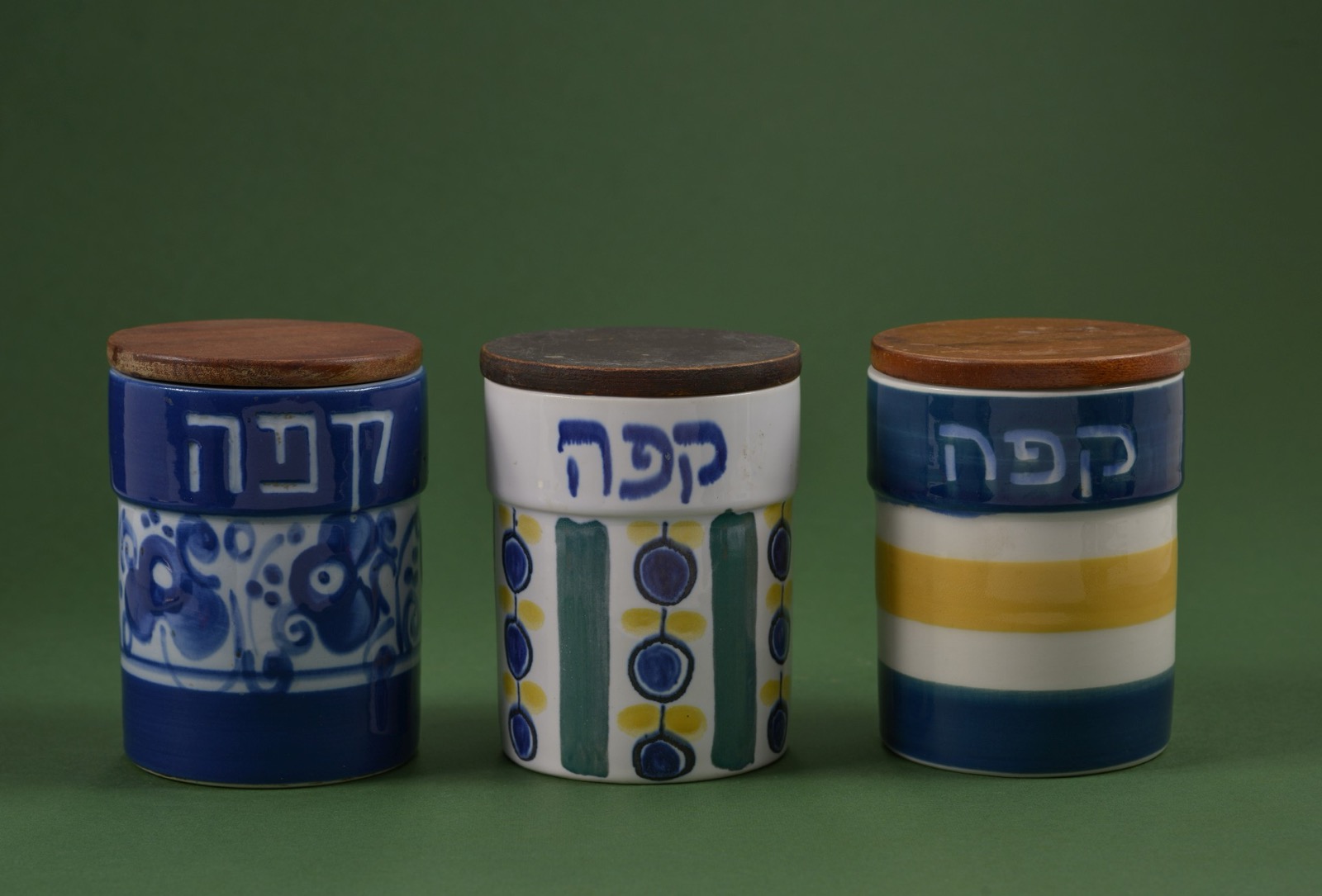 Three Lapid ceramic coffee canisters with wooden lids, each painted with the Hebrew word for coffee